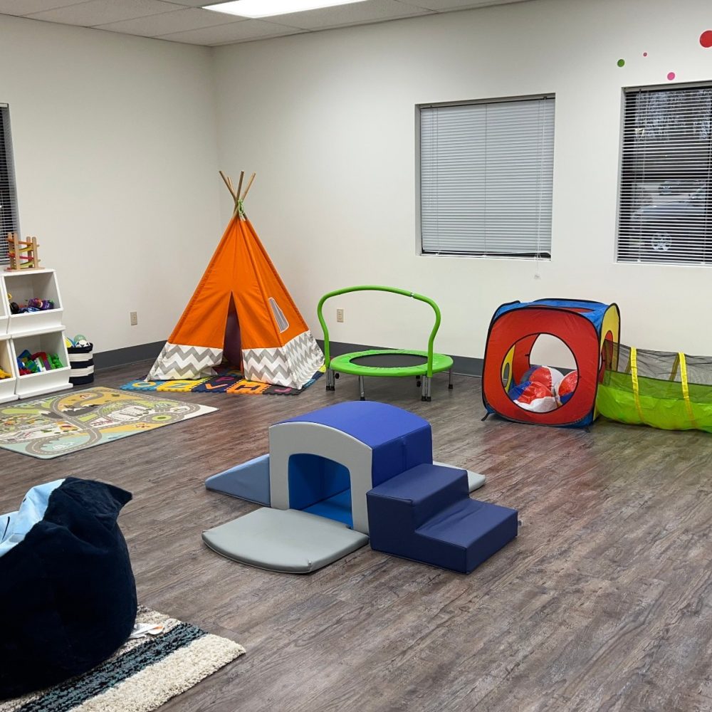 The playroom at ALI. Children's tents, climbing stairs, trampolines, and toys scattered around the room.