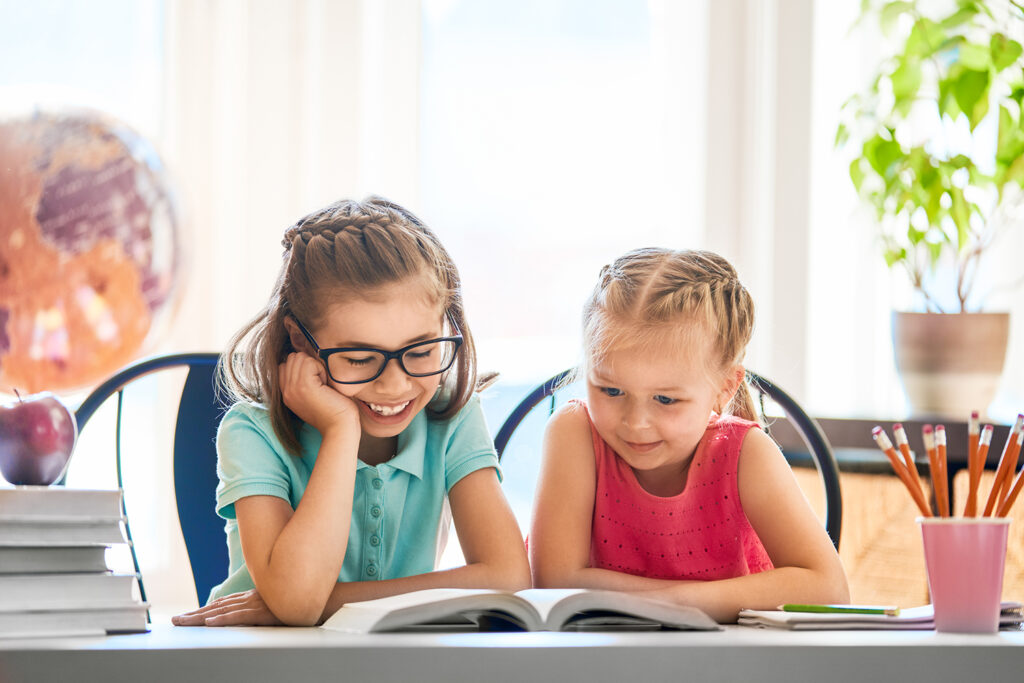 Back to school! Happy cute industrious children are sitting at a desk indoors. Kids are learning in class.