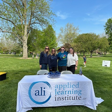 Applied Learning Institute staff smiling at a booth at Dayton Autism Society 5K 2024